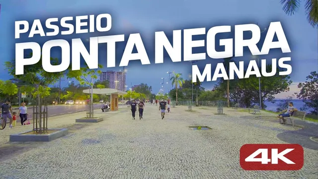 Calçadão da Ponta Negra em pedra portuguesa no fim da tarde, com pessoas caminhando e prédios ao fundo
