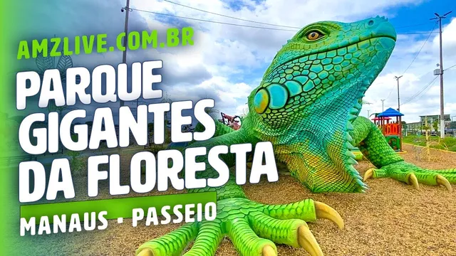 Escultura gigante de iguana verde sobre areia, com brinquedos de playground ao fundo